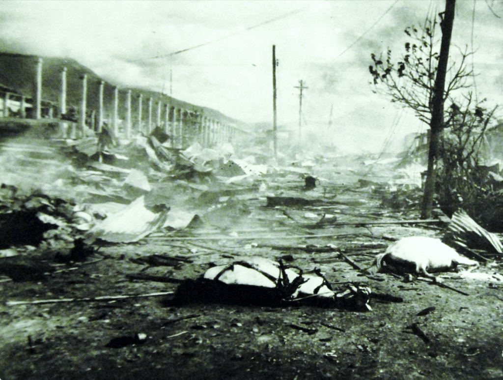 Flattened stalls are spread out under a cloud of smoke. Telephone wires are down. 